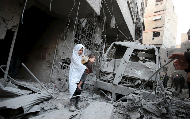 A girl carrying a baby inspects damage in a site hit by what activists said were airstrikes carried out by the Russian air force in the town of Douma, eastern Ghouta in Damascus, Syria January 10, 2016. REUTERS/Bassam Khabieh TPX IMAGES OF THE DAY